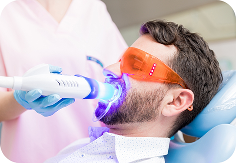 Male dental patient having teeth whitening performed