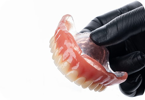 Gloved hand holding a full denture