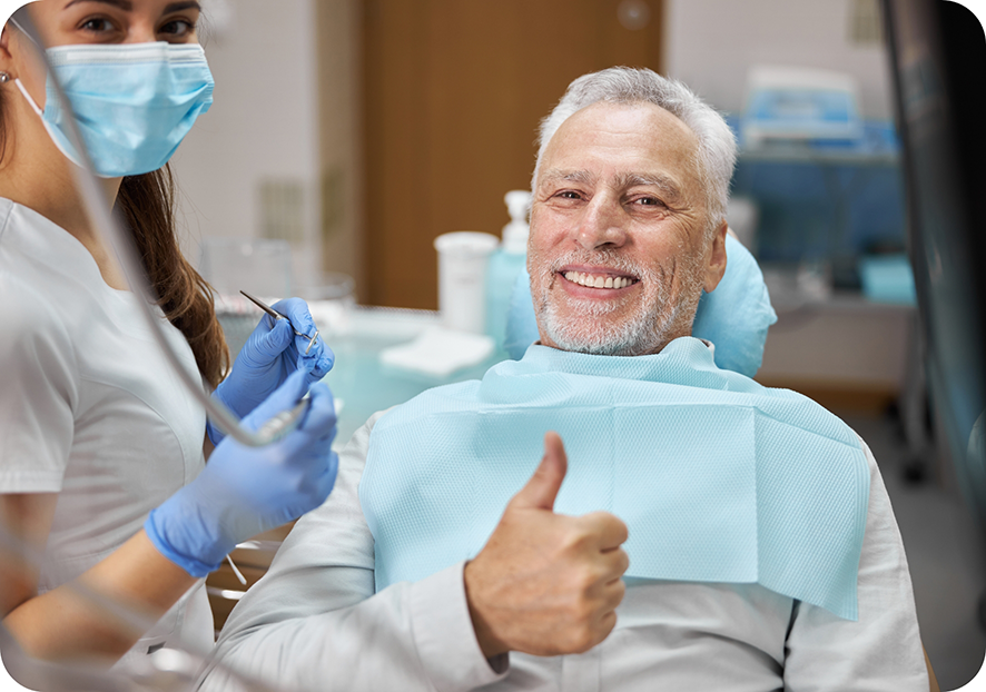 Man sitting back in dental chair giving thumbs up