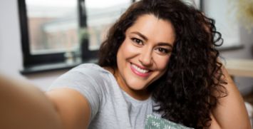 Woman with curly hair smiling and taking selfie