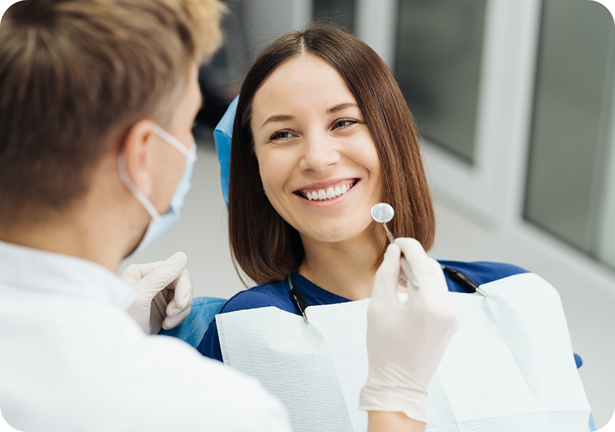Female patient in dental chair smiling up at dentist